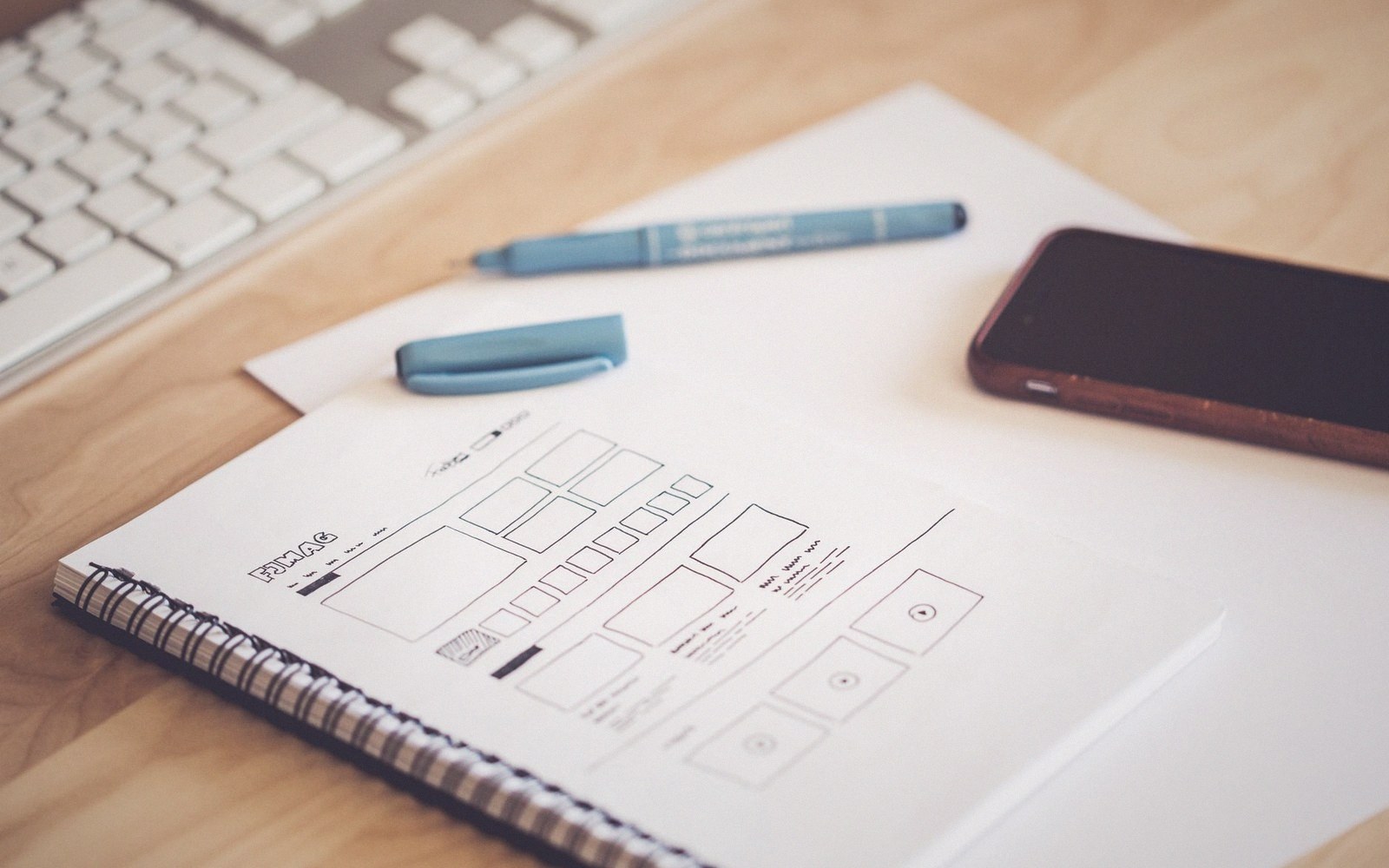 A device on a bench beside a notebook of interface sketches