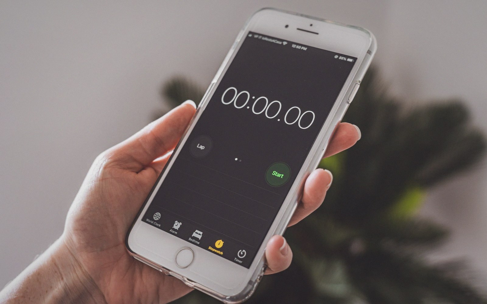 A hand holds a smartphone displaying a stopwatch app reset to zero